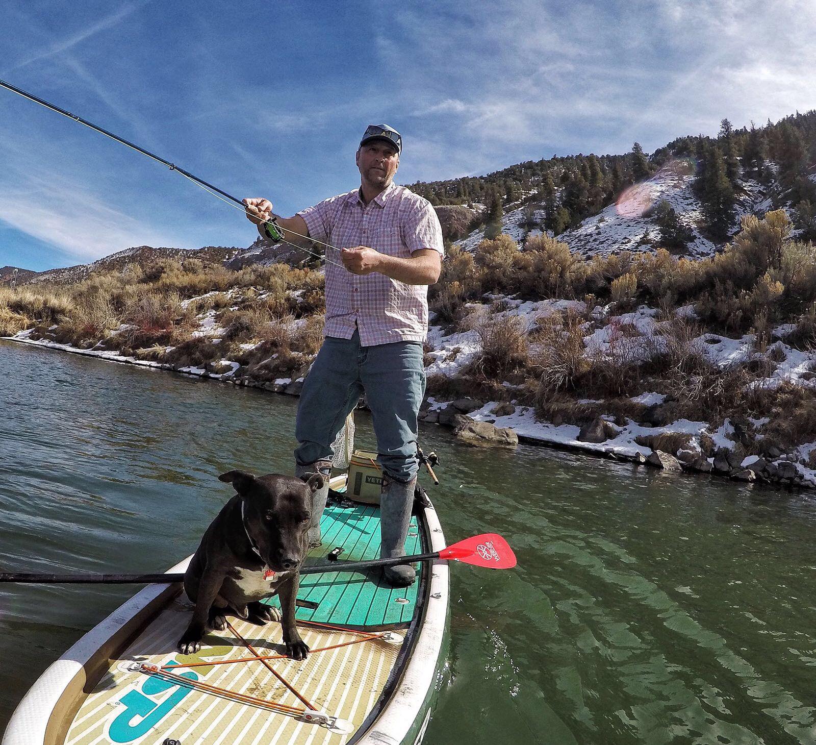 Man and his dog on a fishing SUP with all his gear