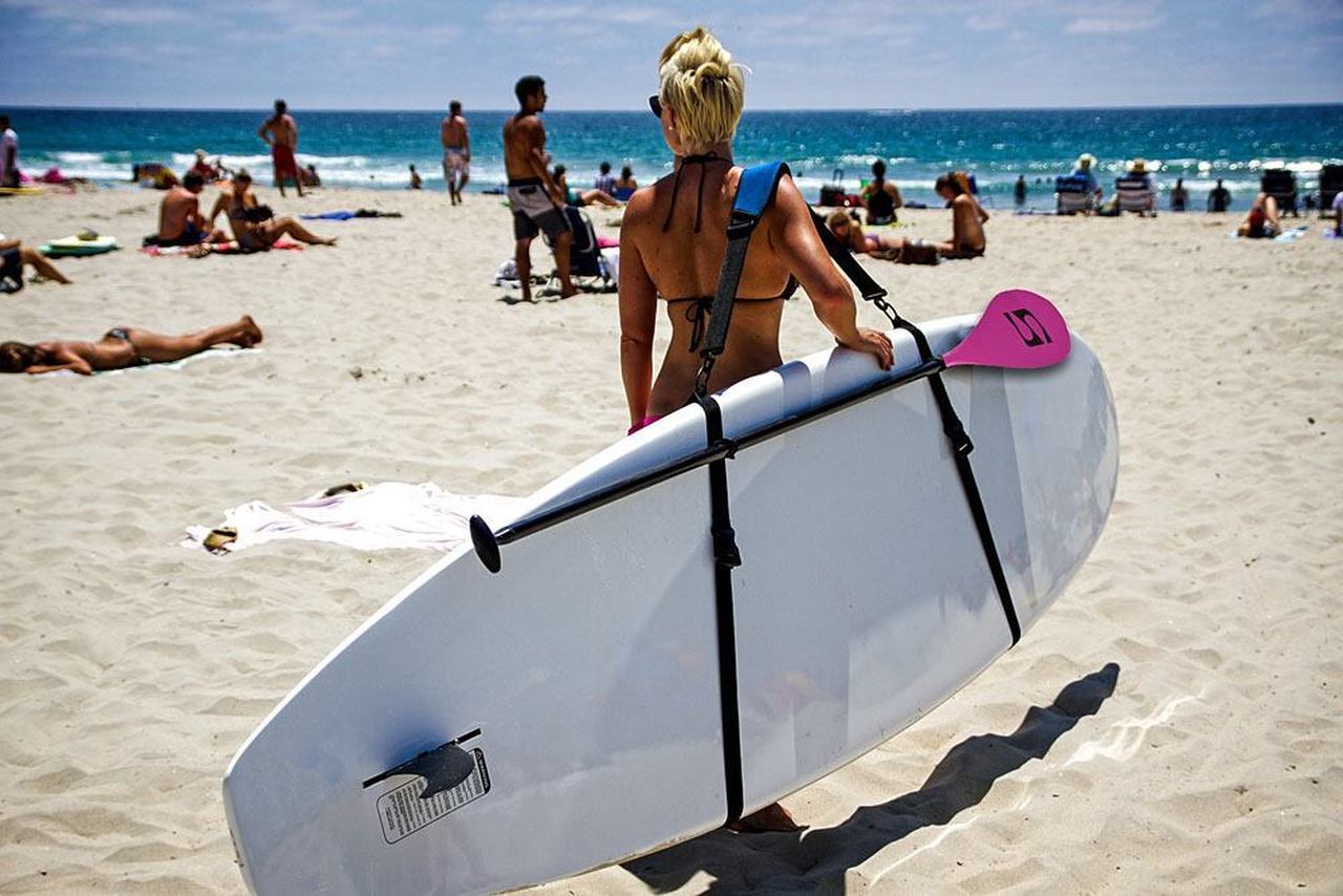 Woman carrying SUP using paddle board carrier straps