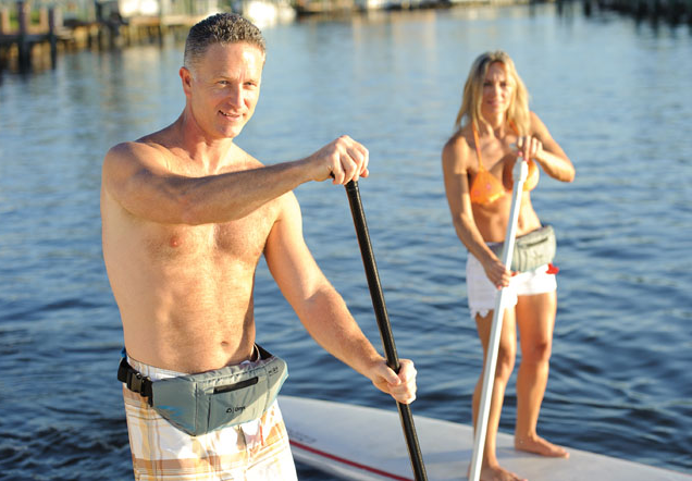 Couple stand up paddle boarding with PFDs strapped to their waist