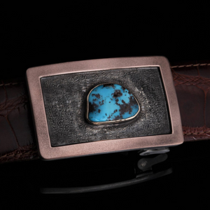 The image showcases a captivating Sterling Silver Buckle adorned with a vibrant Turquoise centerpiece. The buckle is meticulously crafted with intricate detailing, reflecting the craftsmanship and artistry of the maker.