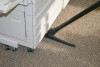 A photo of the sidewinder cleaning under a large printer with about 5 inches of the tool under the printer.