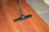 A floor brush on a wand cleaning a hardwood floor.