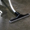 A squeegee tool attached to an S-wand cleaning a liquid off of a warehouse floor.