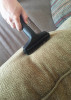 Person vacuuming couch with upholstery tool with slide-on brush.