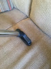 Upholstery tool with slide-on brush cleaning a couch cushion.