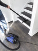 Person using Sidewinder connected to the C105 vacuum to clean wood staircase.