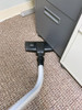 Combination tool cleaning underneath filing cabinet in office.