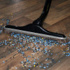 Close up of floor brush cleaning up debris on hardwood floor.