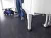 Person using Sidewinder connected to the C105 vacuum to clean under a piano.