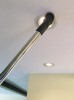 Dust brush attached to chrome wand cleaning inset light on ceiling.