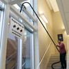 Person using Reach 130 degree adapter wand with camera connected and Sidewinder brush cleaning white painted metal beam in front of windows.