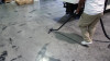 Person cleaning concrete floor with S-wand and floor brush.