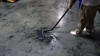 Person cleaning concrete floor with S-wand and floor brush.