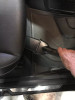 Crevice tool cleaning underneath the front of a car seat.