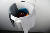 Towels and cleaning supplies in wall mounted bucket.