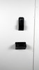 Black plastic wall mount pieces mounted onto white wall.