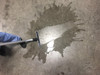 An S-Wand with a squeegee attached cleaning a spilled liquid off of a concrete floor.