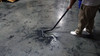 Person cleaning concrete floor with S-wand and floor brush.