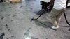 Person cleaning concrete floor with S-wand and floor brush.