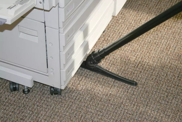 A photo of the sidewinder cleaning under a large printer with about 5 inches of the tool under the printer.