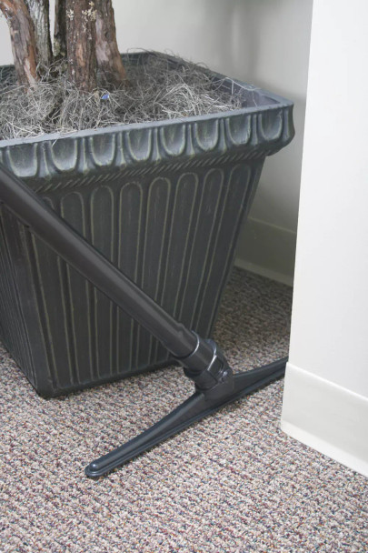A sidewinder tool between a wall and a potted plant.