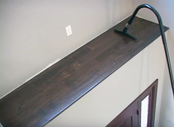 A 130 Degree Curved Extension Wand cleaning a ledge above a doorway.