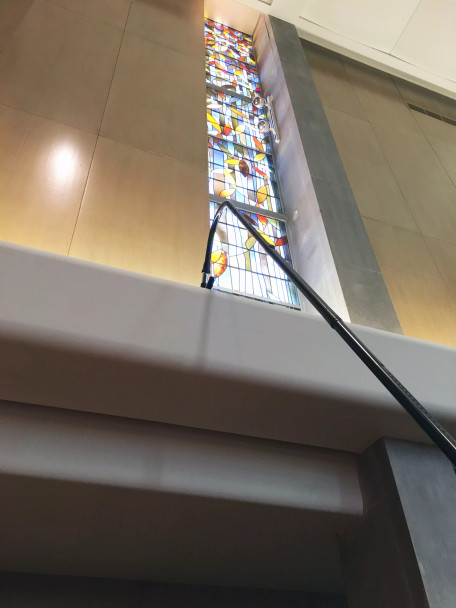 Reach with Sidewinder brush cleaning ledge in a church.