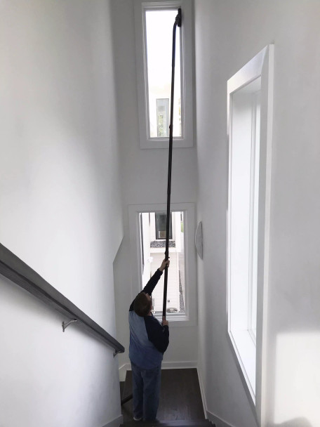 Person cleaning window that's 10 to 15 feet up in a stairwell.