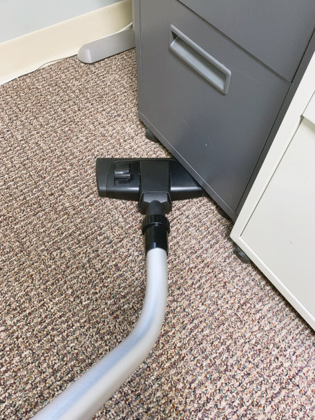 Combination tool cleaning underneath filing cabinet in office. Combination tool cleaning underneath filing cabinet in office.