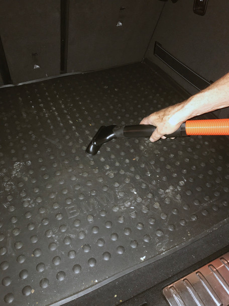 Upholstery tool cleaning the trunk of a car.