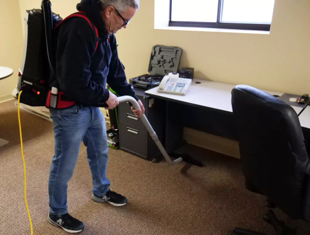 Person with Perfect Power 6 quart backpack vacuum cleaning office space.