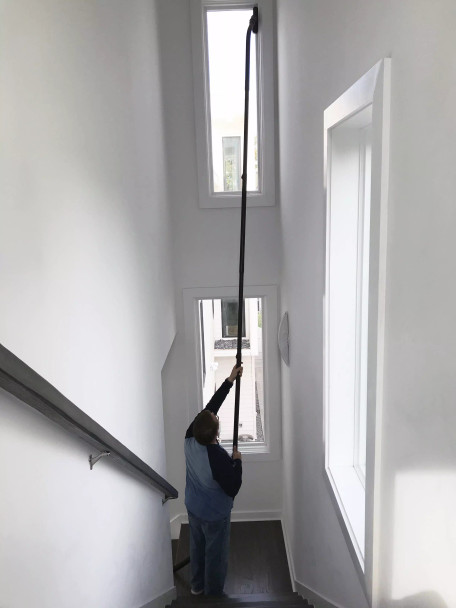 Person cleaning window that's 10 to 15 feet up in a stairwell.