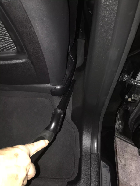 Crevice tool cleaning in between a seat and door in a car.