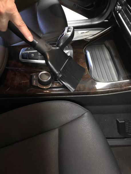 Dust brush cleaning console in car.