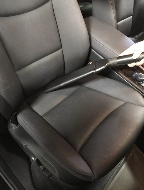 Crevice tool cleaning between the top and bottom of car seat.