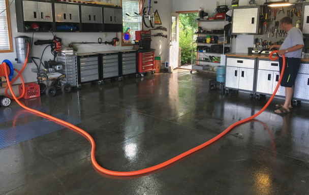 Person cleaning counter in garage with hose pulled out of the reel across the garage.