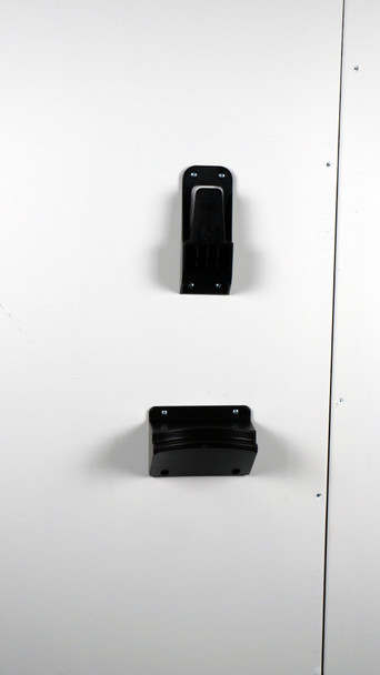 Black plastic wall mount pieces mounted onto white wall.