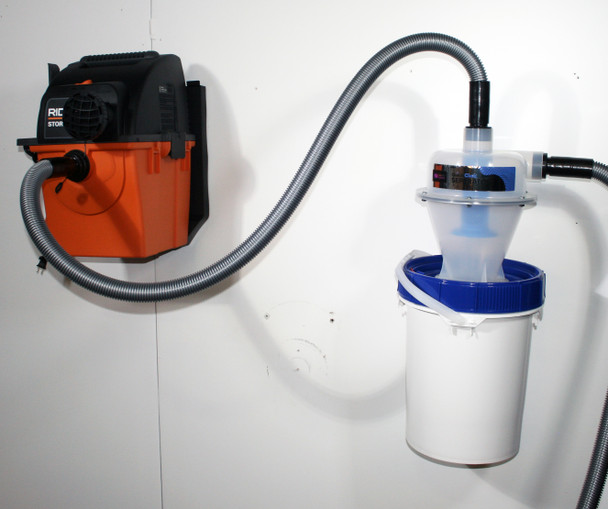 Vacuum and Quick Click separator bucket mounted onto wall and connected via hose.