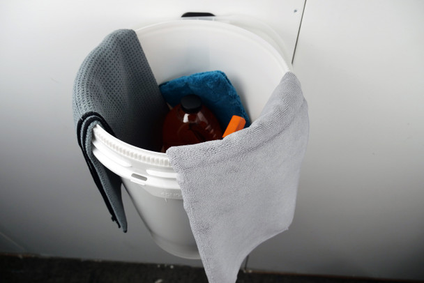 Towels and cleaning supplies in wall mounted bucket.