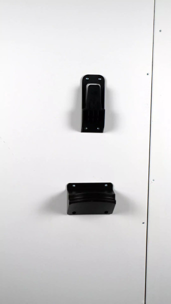 Black plastic wall mount pieces mounted onto white wall. Black plastic wall mount pieces mounted onto white wall.