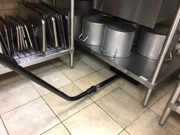 Cleaning under kitchen shelves using an S-wand and floor brush.