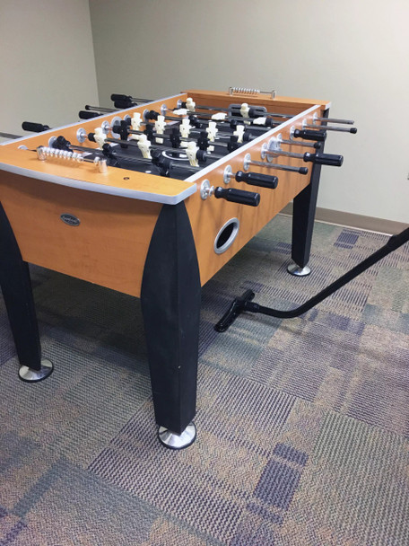 Cleaning carpet under foosball table using an S-wand and carpet tool.