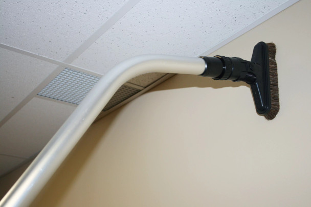 A sidewinder brush on a wand cleaning high up on a wall.