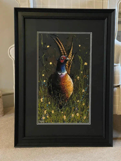 Pheasant painting with lots of colour shown in a black frame 