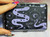 A black mystical print case with purple snakes covered in moon phases and stars, the case is covered in purple stars, hearts and eyes.This sleek compact case can fit joints, cigs, and credit cards and birth control pills.