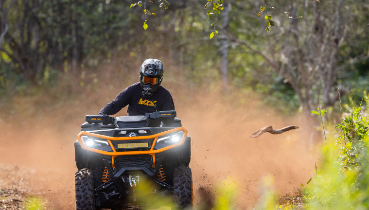 Rider on a Can-Am ATV kicking up dust on a dirt trail