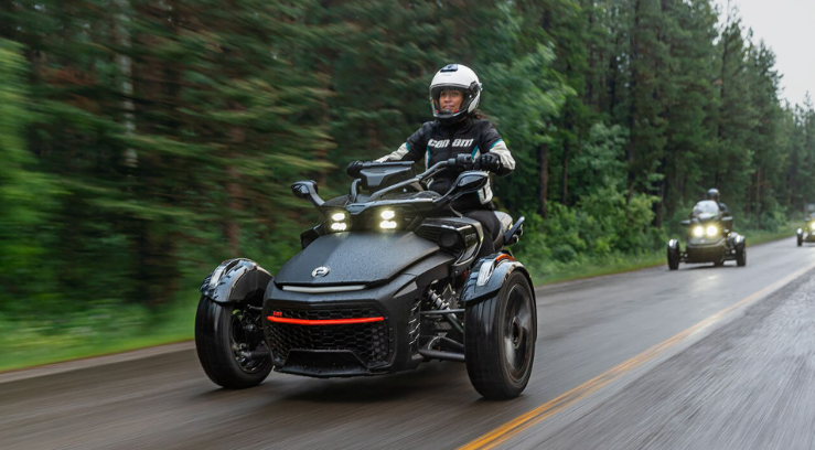 Rider on a Can-Am Spyder three-wheel motorcycle on a wet forest road