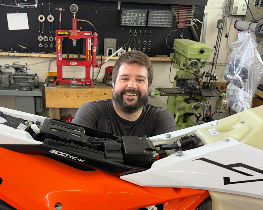Jake Norris smiling behind a KTM 300 XC-W in the shop