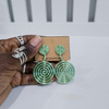 Hand holding contemporary cultural jewelry Fumi green 3D printed symbolic statement earrings by dallas brand zuri perle