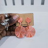 Hand holding contemporary cultural jewelry Fumi salmon 3D printed symbolic statement earrings by dallas brand zuri perle